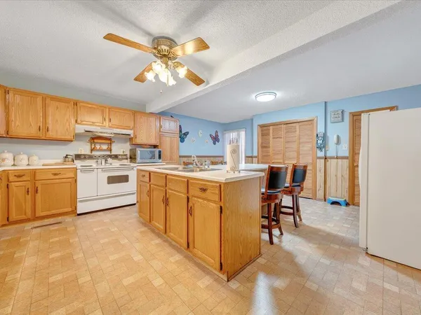 a kitchen with a refrigerator a sink dishwasher a dining table and chairs with wooden floor