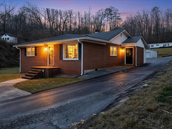 a front view of house with yard and trees in the background
