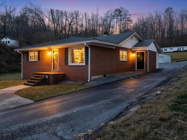 a front view of house with yard and trees in the background