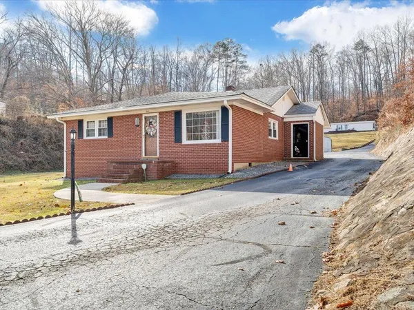 a view of a house next to a big yard with large tree