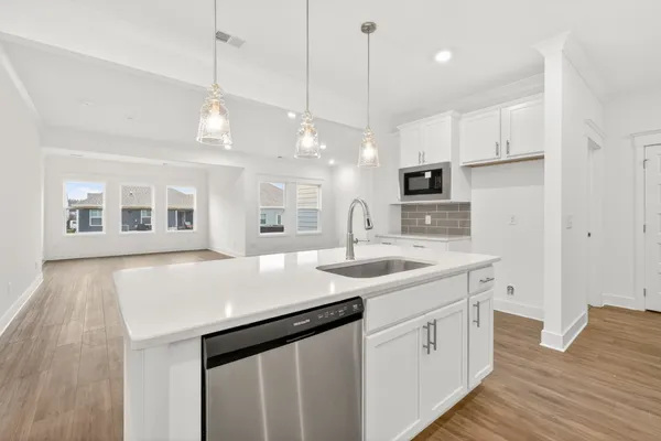 a large kitchen with kitchen island a stove a sink a center island and wooden floor