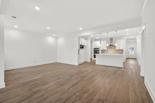 a view of an empty room with window and wooden floor