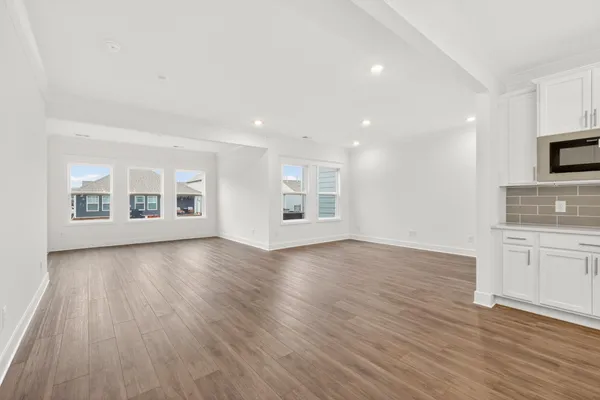 a view of a big room with wooden floor and windows