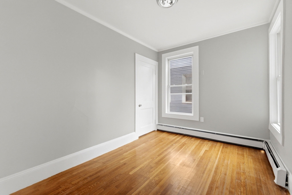 60 Tudor Street, Unit 1 Lynn, MA 01902 - Photo 13 of 19 an empty room with wooden floor and windows
