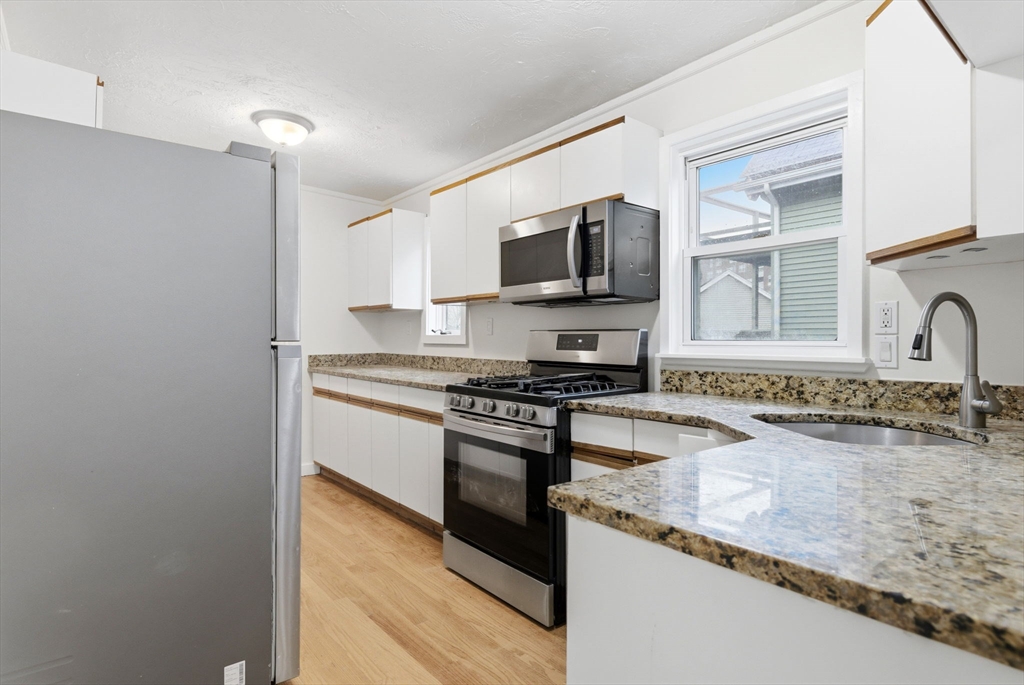 60 Tudor Street, Unit 1 Lynn, MA 01902 - Photo 6 of 19 a kitchen with stainless steel appliances granite countertop a sink stove and microwave