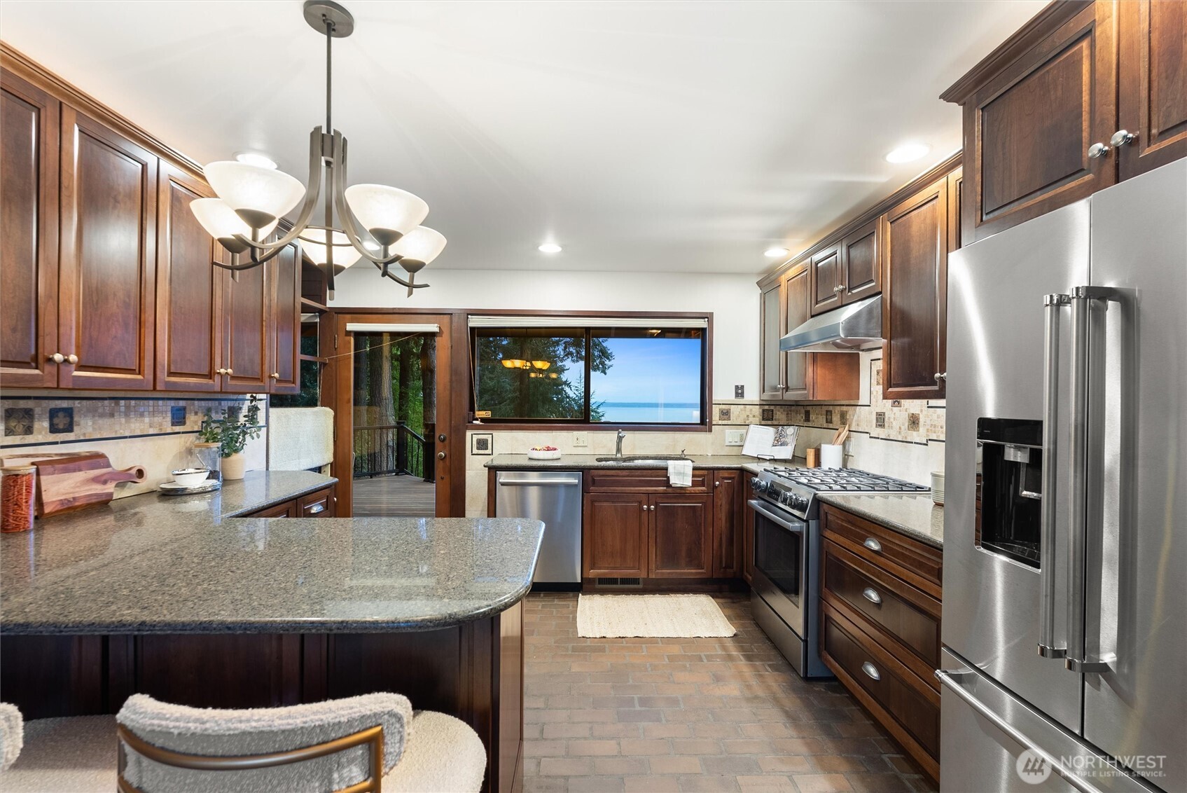 6920 160th Street Southwest Edmonds, WA 98026 - Photo 14 of 40 a kitchen with stainless steel appliances granite countertop a sink a stove top oven a refrigerator cabinets and chairs