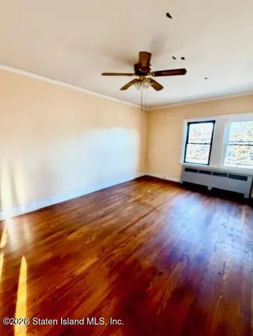 a view of lot of an empty room with wooden floor and a window