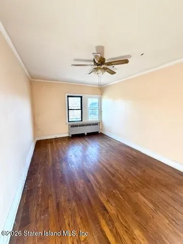 an empty room with wooden floor chandelier fan and windows