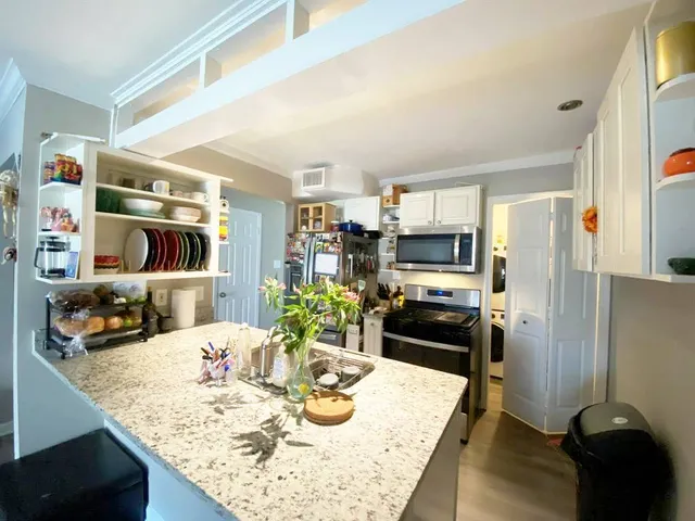 a kitchen with stainless steel appliances kitchen island granite countertop a table chairs in it and wooden floors