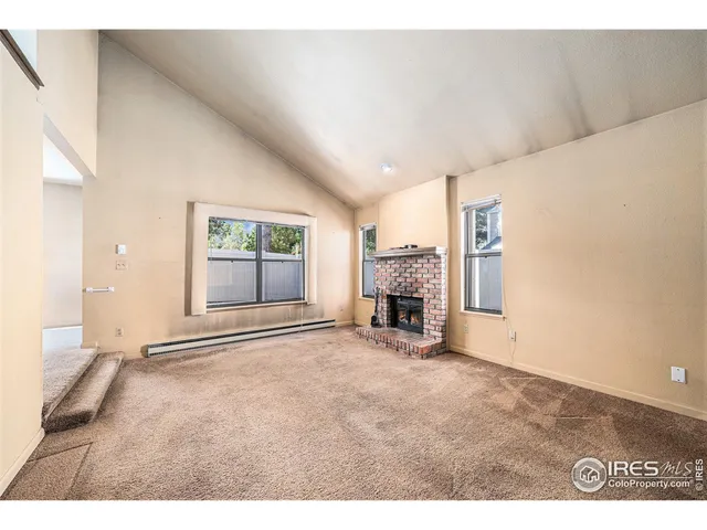 a view of an empty room with a fireplace and a window