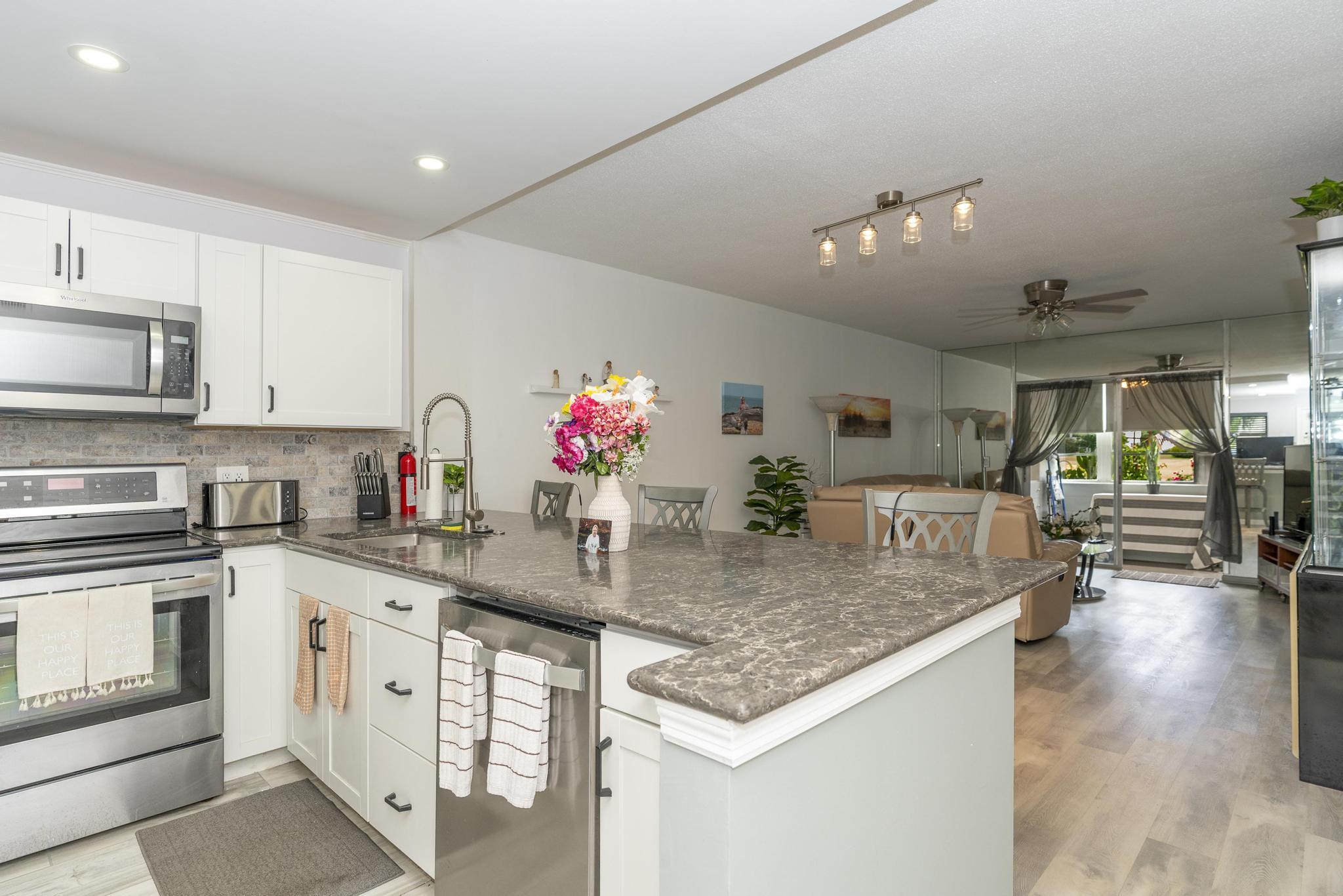 a kitchen with stainless steel appliances granite countertop a sink dishwasher a stove and white cabinets with wooden floor