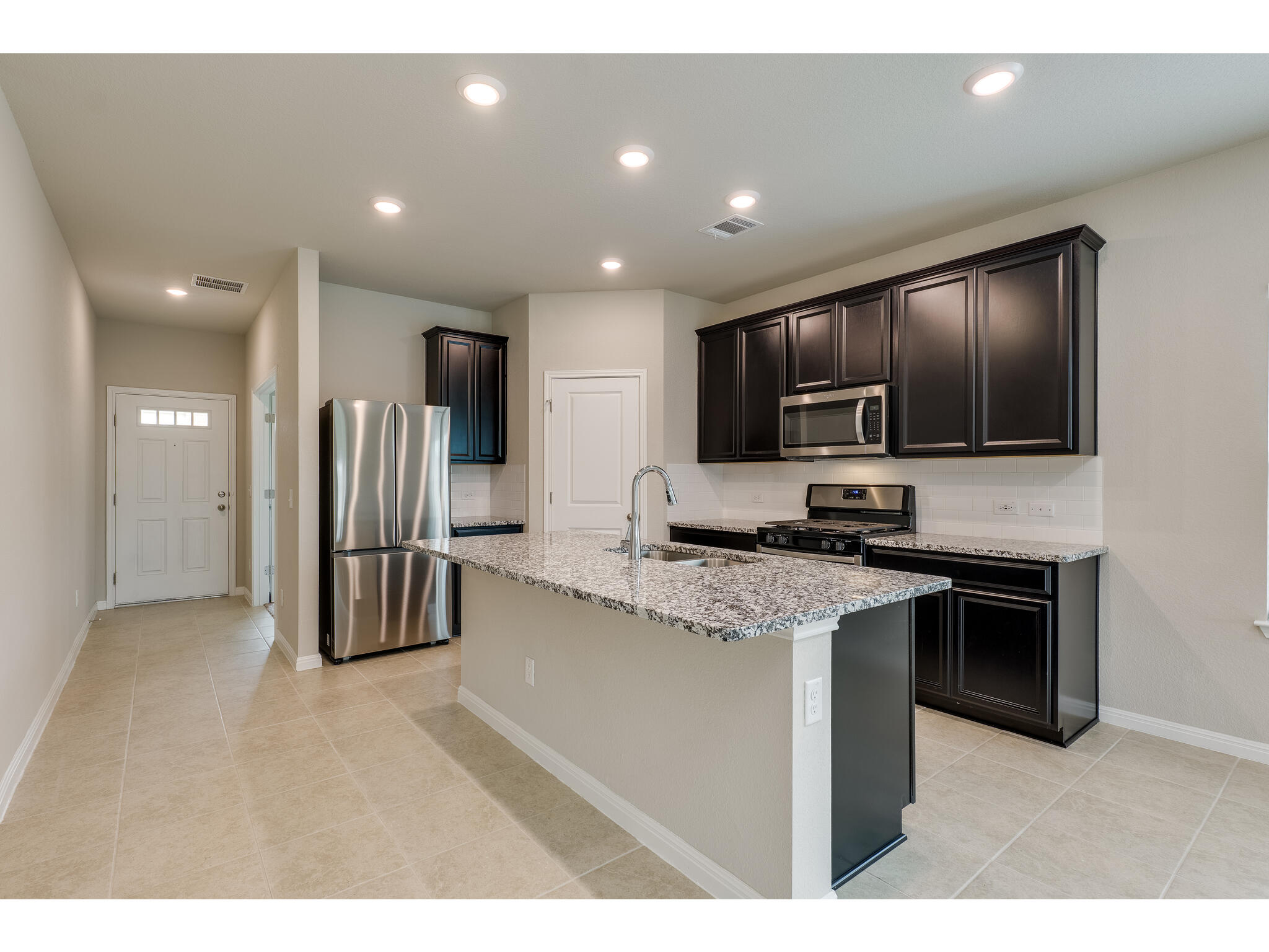 111 Grapefruit Road Hutto, TX 78634 - Photo 12 of 39 Kitchen featuring stainless steel appliances, a sink, a kitchen island with sink, light stone counters, and baseboards