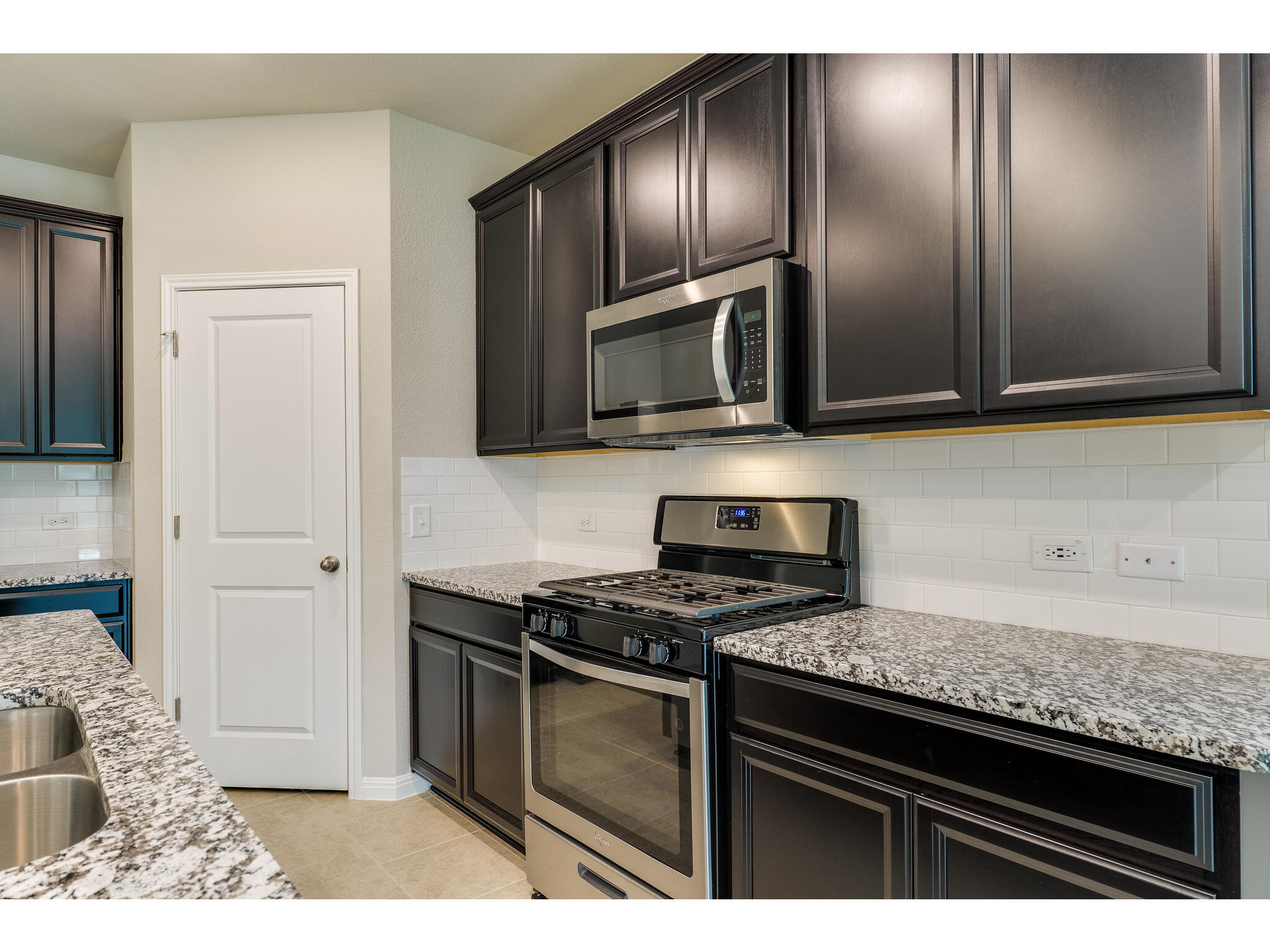 111 Grapefruit Road Hutto, TX 78634 - Photo 13 of 39 Kitchen featuring stainless steel appliances, tasteful backsplash, light stone countertops, and light tile patterned flooring