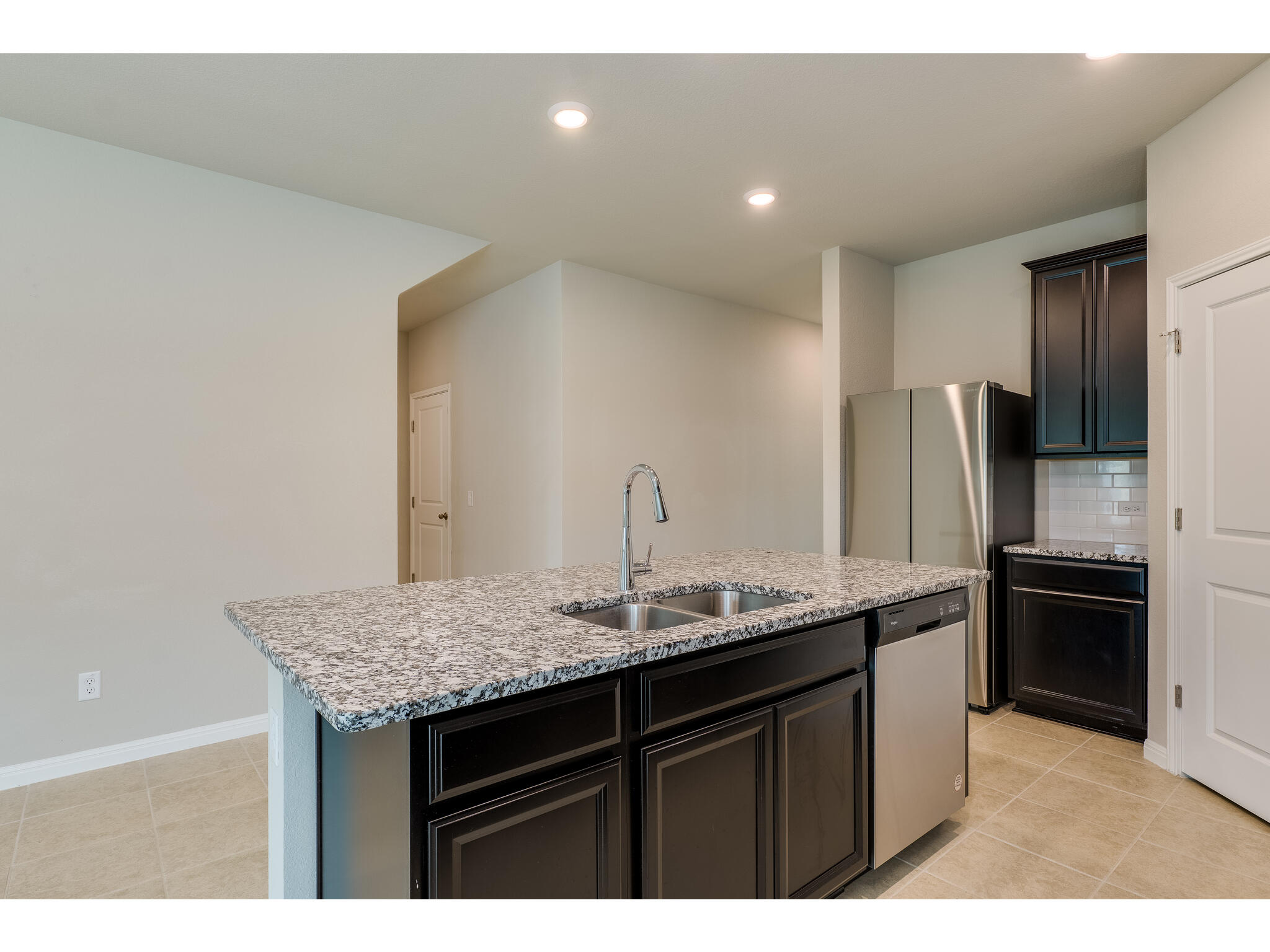 111 Grapefruit Road Hutto, TX 78634 - Photo 14 of 39 Kitchen with appliances with stainless steel finishes, a sink, a center island with sink, light stone counters, and light tile patterned floors