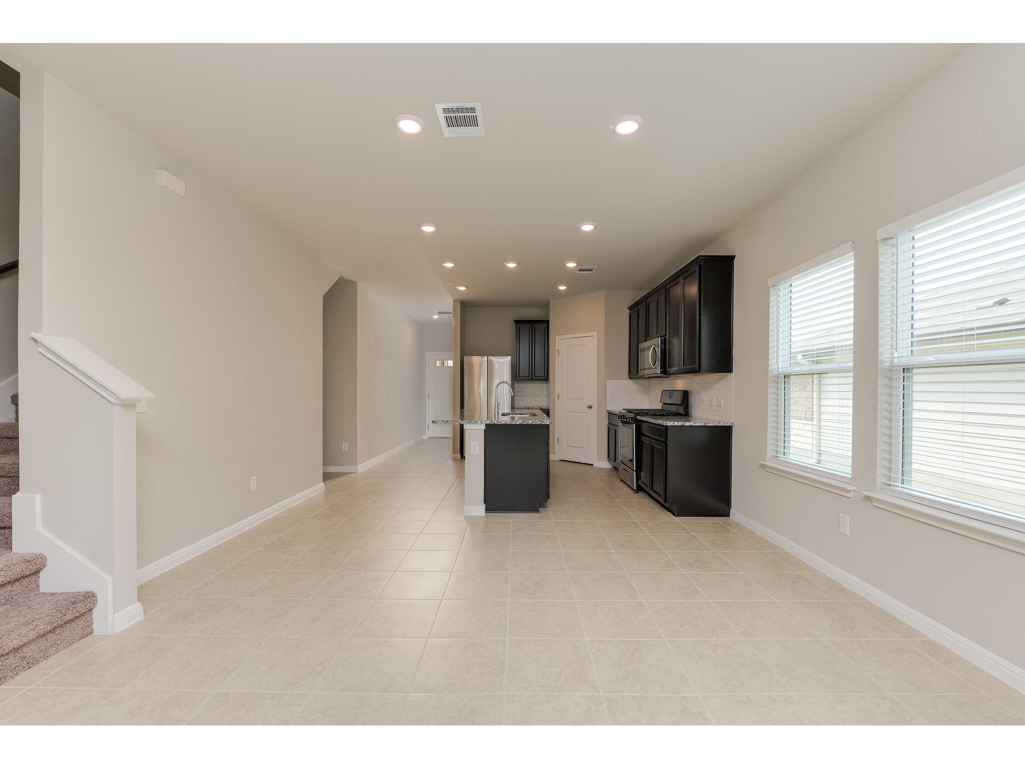 111 Grapefruit Road Hutto, TX 78634 - Photo 39 of 39 Kitchen with appliances with stainless steel finishes, open floor plan, light stone counters, an island with sink, and light tile patterned flooring