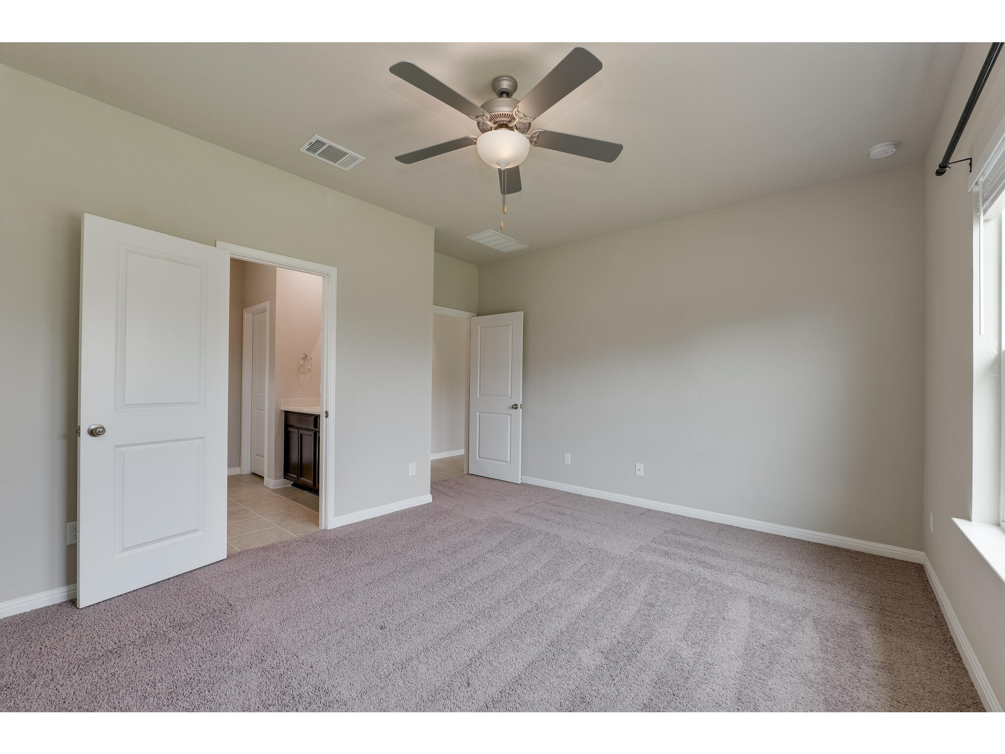 111 Grapefruit Road Hutto, TX 78634 - Photo 19 of 39 Unfurnished bedroom with light carpet, baseboards, a ceiling fan, and connected bathroom