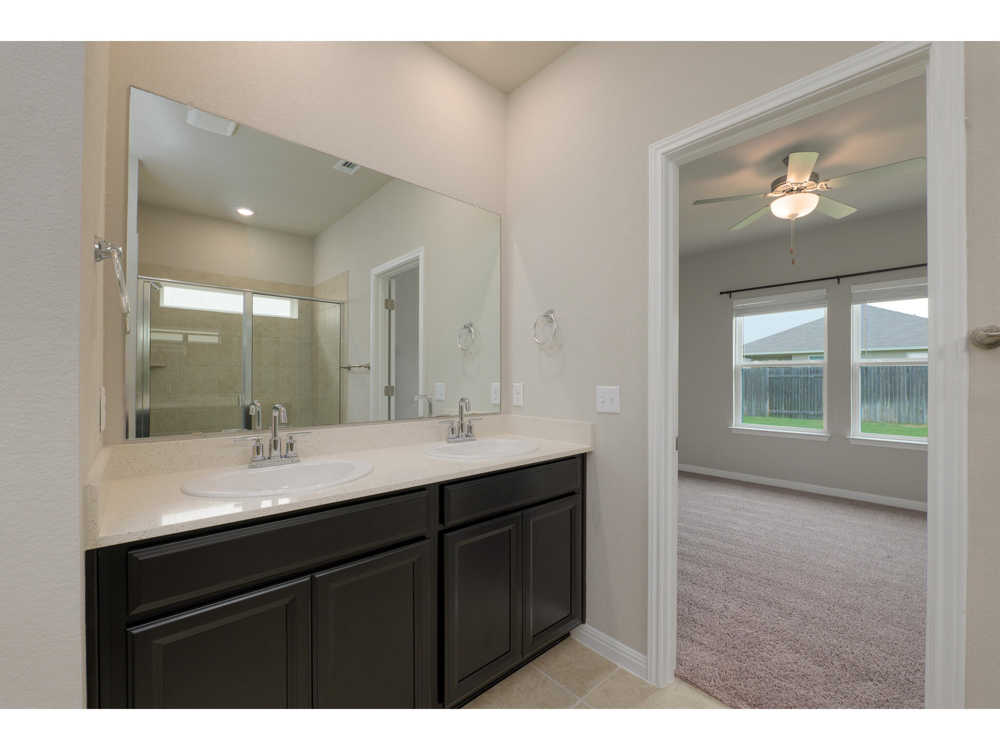 111 Grapefruit Road Hutto, TX 78634 - Photo 22 of 39 Full bathroom with a stall shower, double vanity, tile patterned flooring, ceiling fan, and baseboards
