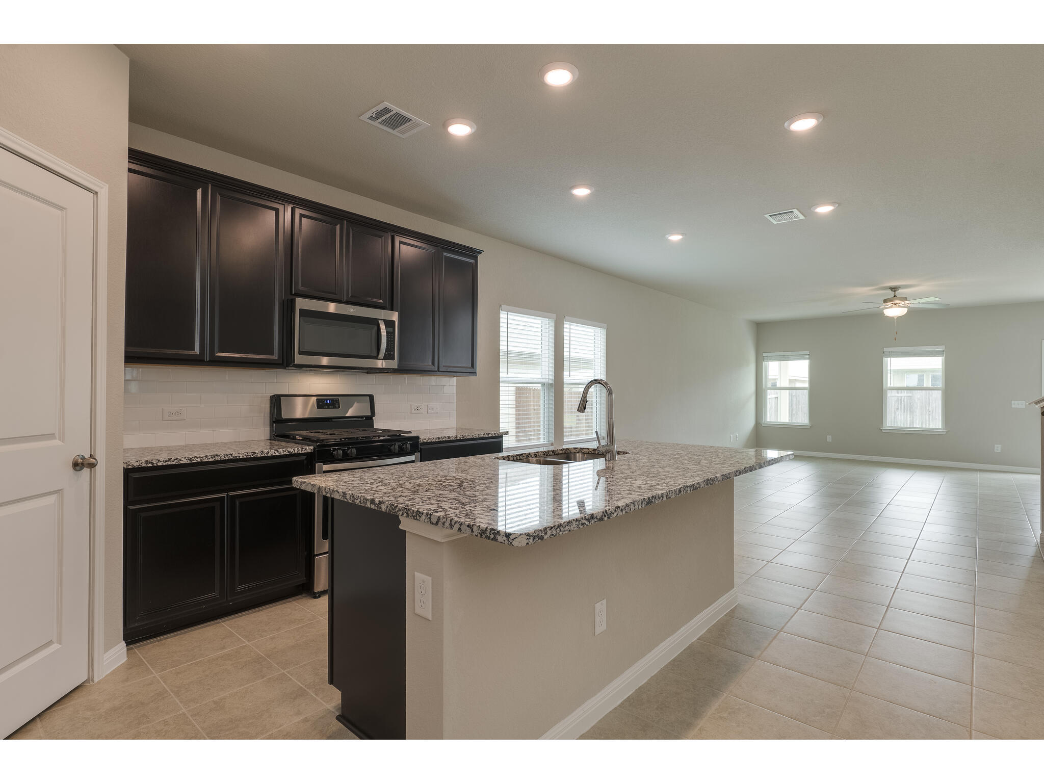 111 Grapefruit Road Hutto, TX 78634 - Photo 38 of 39 Kitchen with appliances with stainless steel finishes, a sink, open floor plan, light tile patterned floors, and a kitchen island with sink