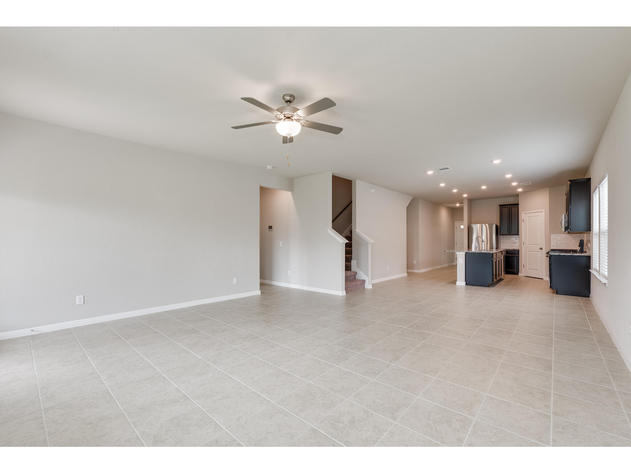 111 Grapefruit Road Hutto, TX 78634 - Photo 4 of 39 Unfurnished living room with stairs, a ceiling fan, a sink, baseboards, and recessed lighting