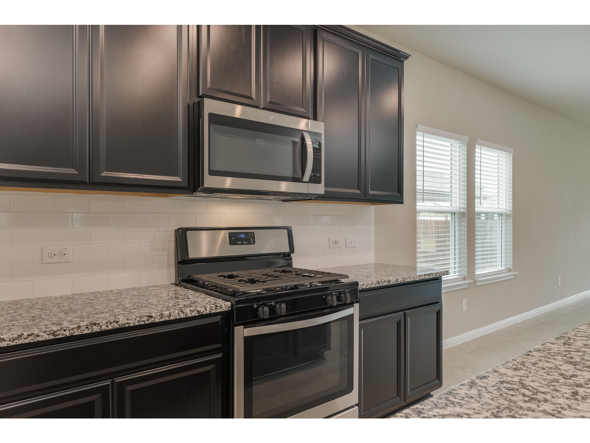 111 Grapefruit Road Hutto, TX 78634 - Photo 7 of 39 Kitchen featuring appliances with stainless steel finishes, tasteful backsplash, baseboards, and light stone countertops