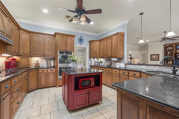 a kitchen with kitchen island granite countertop a sink counter top space appliances and cabinets