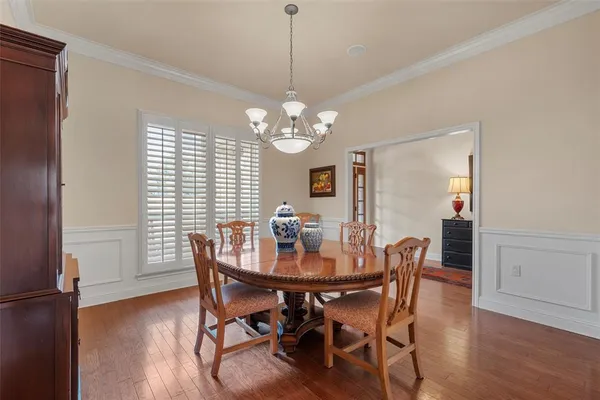 a dining room with wooden floor a chandelier a wooden table and chairs