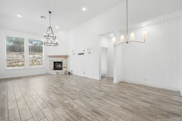 an empty room with wooden floor fireplace and windows