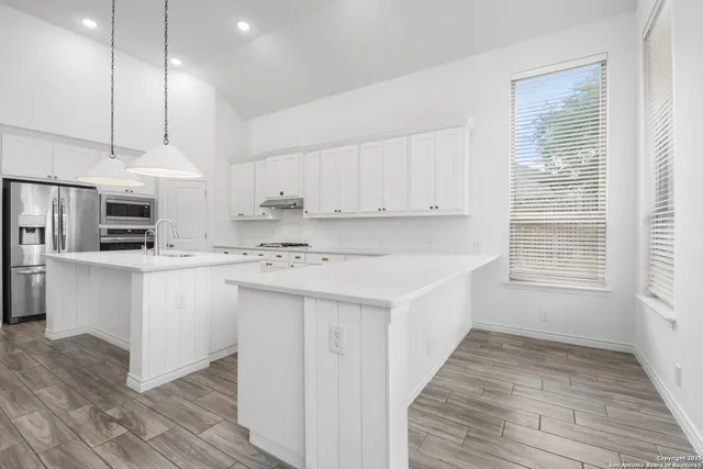 a kitchen with kitchen island granite countertop a sink a counter space appliances and cabinets