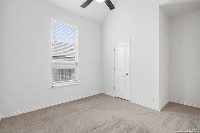 an empty room with chandelier fan and window