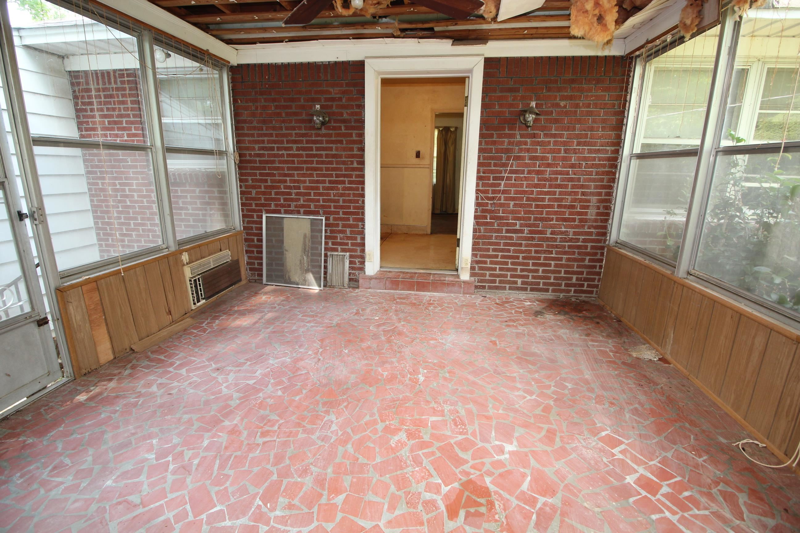 1079 Alden Road Memphis, TN 38116 - Photo 26 of 40 Enclosed porch featuring a red brick wall, a red irregular tile floor, and wood paneling below multiple windows