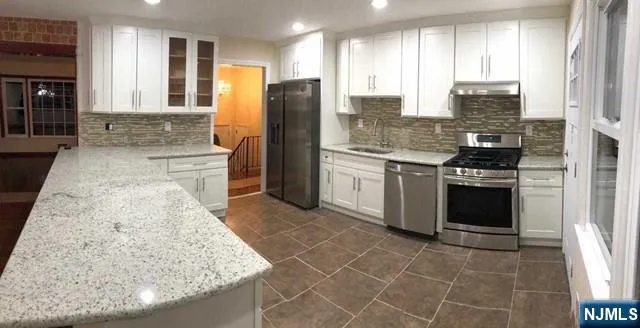 a kitchen with stainless steel appliances granite countertop a stove a sink and a refrigerator
