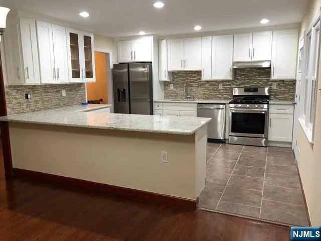 a kitchen with stainless steel appliances granite countertop a refrigerator a stove and a sink