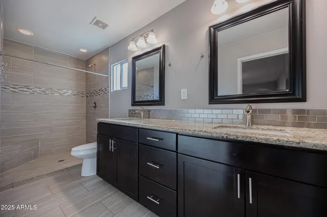 a bathroom with a granite countertop toilet sink and a mirror