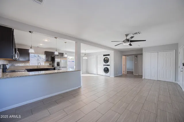 a large kitchen with stainless steel appliances a large counter top a sink a refrigerator and a window