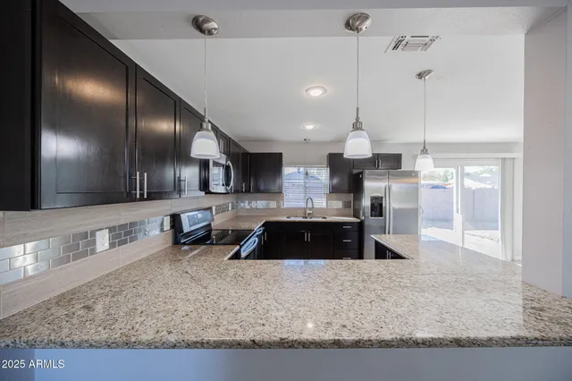 a large kitchen with stainless steel appliances granite countertop a stove a sink and a granite counter top