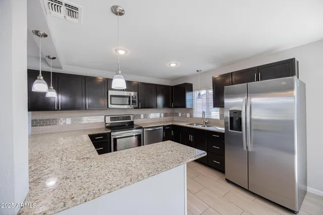 a kitchen with stainless steel appliances granite countertop a refrigerator a sink a stove and oven