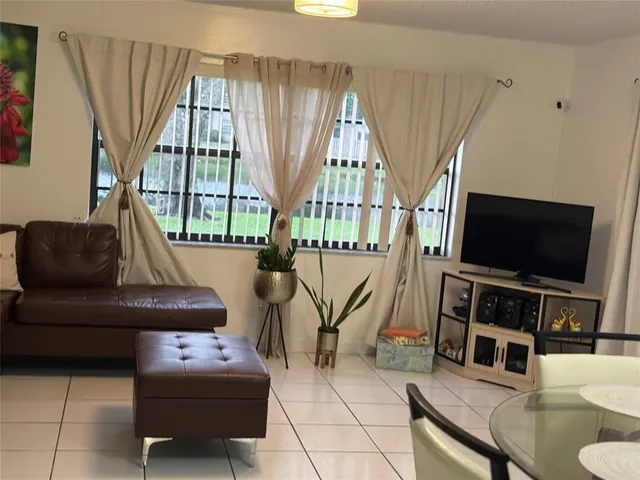 a living room with furniture a flat screen tv and a large window