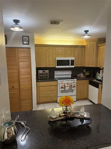 a kitchen with stainless steel appliances kitchen island granite countertop a stove refrigerator and cabinets
