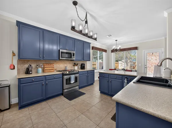 a kitchen with stainless steel appliances granite countertop wooden cabinets a stove a sink a oven with a dining table and chairs