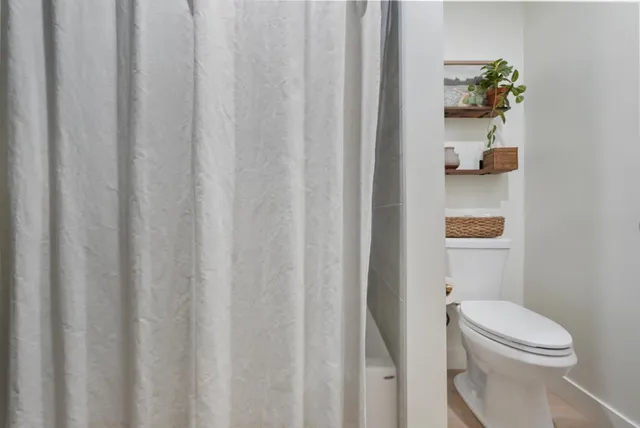 a bathroom with a toilet and a shower curtain