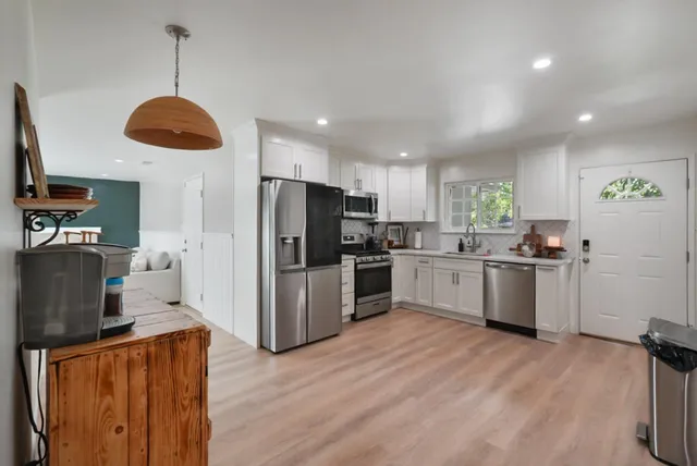 a kitchen with stainless steel appliances granite countertop a refrigerator a stove a sink dishwasher and a refrigerator with wooden floor