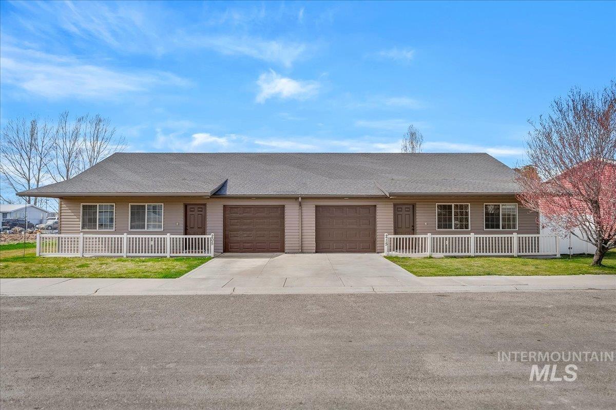 Ranch-style house featuring a shingled roof, driveway, and an attached garage