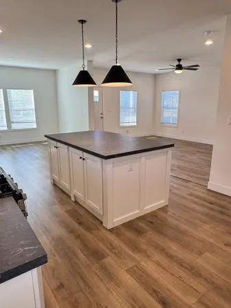 a kitchen with stainless steel appliances granite countertop a sink a stove a dining table and chairs with wooden floor