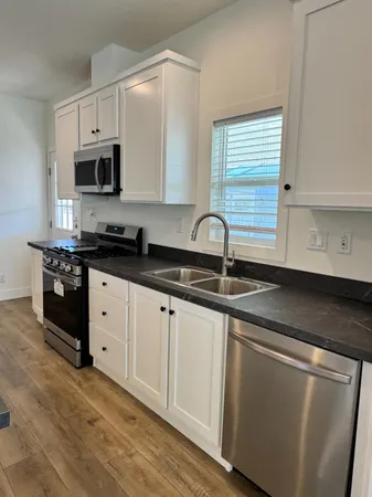 a kitchen with granite countertop white cabinets and black appliances