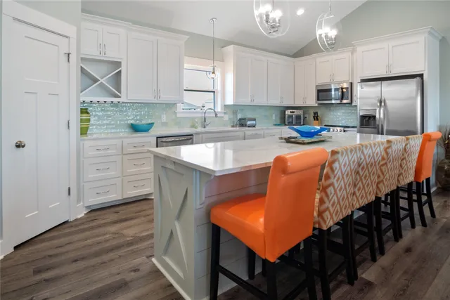 a large kitchen with cabinets a sink dishwasher a stove and a dining table with wooden floor