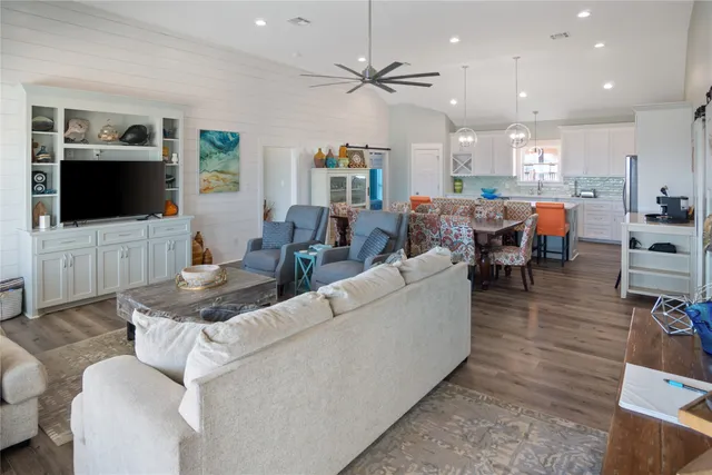 a living room with furniture kitchen view and a flat screen tv