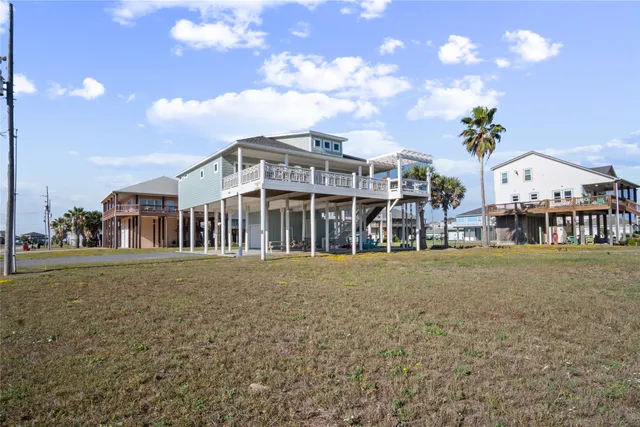 a large living room with large couches chandelier and kitchen view