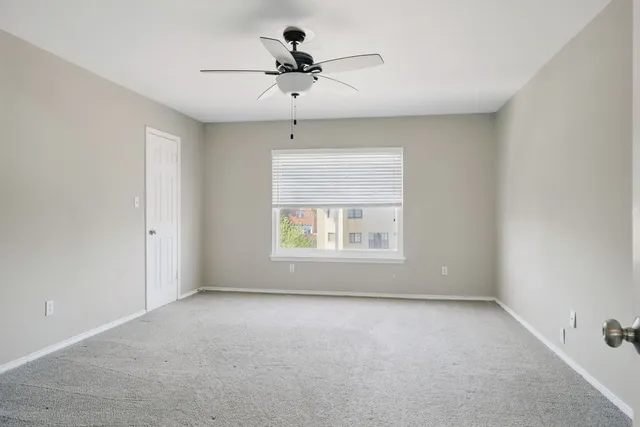 an empty room with a ceiling fan and window