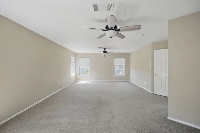 an empty room with a chandelier fan and windows