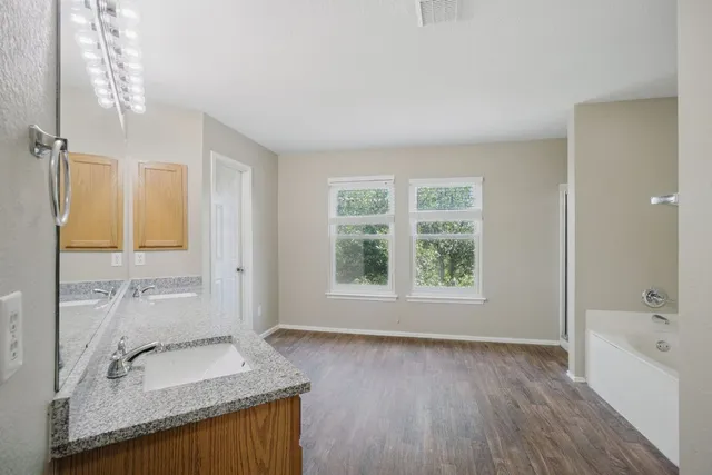 a bathroom with a granite countertop tub sink and mirror